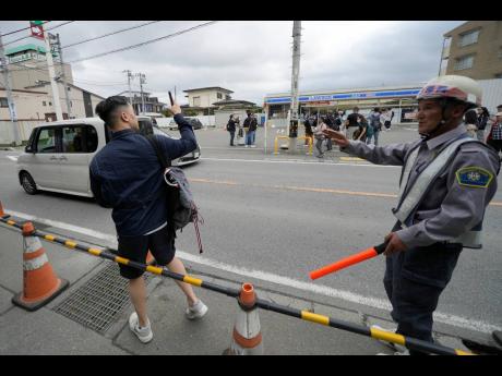 Credit: AP Eugene Hoshiko
A security guard redirects a tourist outside of the construction site of a barricade near the Lawson convenience store on Tuesday, April 30, 2024, at Fujikawaguchiko town, Yamanashi Prefecture, central Japan. The town of Fujikawaguchiko, known for a numbe