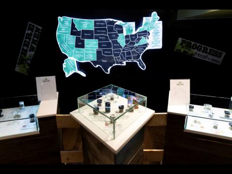 A map of cannabis legalisation in the United States glows behind flower displays at the Empire Cannabis Club, November 16, 2022, in New York.