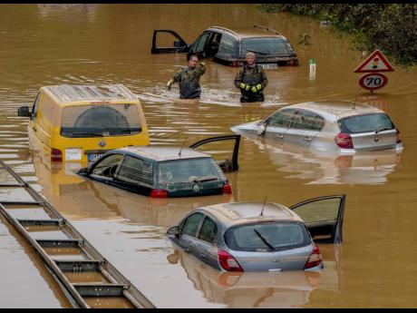 Helpers check for victims in flooded cars on a road in Erftstadt, Germany, July 17, 2021. 