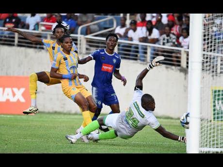 Mount Pleasant’s Devonte Campbell (second right) scores past Waterhouse goalkeeper Kemar Foster during yesterday’s Jamaica Premier League second-leg semi-final  match at Sabina Park. Looking on are Waterhouse midfielder Shemar Boothe (left) and defende