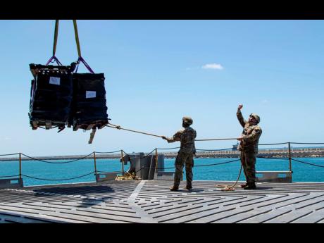 US Army soldiers assigned to the 7th Transportation Brigade (Expeditionary) use a rope to stabilise humanitarian aid while it is lifted by a crane aboard the MV Roy P. Benavidez to support the Joint Logistics Over-the-shore operation, in the Port of Ashdod