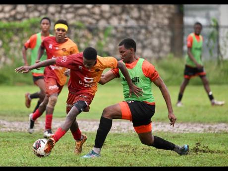 Spanish Town High’s Javid Page (centre) dribbles away from Daeshawn Tate of Tivoli High during a Manning Cup match at the Spanish Town Prison Oval on Monday, October 9, 2023.