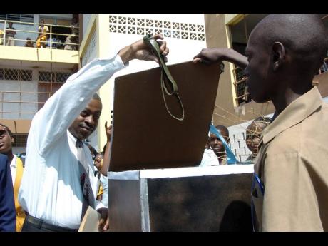 In this March 2006 photo, Dennis Kelly, then principal of Charlie Smith High School, buries a strap in a makeshift coffin to symbolise the discontinuation of corporal punishment at the institution.