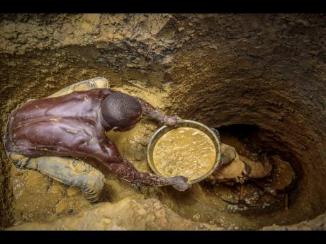 Miners extract mud they hope contains gold at a gold mining site at which adults and youth work in the village of Mawero, on the outskirts of Busia town, in eastern Uganda on October 18, 2021. Billons of dollars worth of gold is smuggled out of Africa each