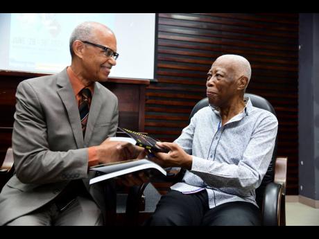Nicholson (right) presents Justice Patrick Brooks, president of the Court of Appeal, with a copy of his book.