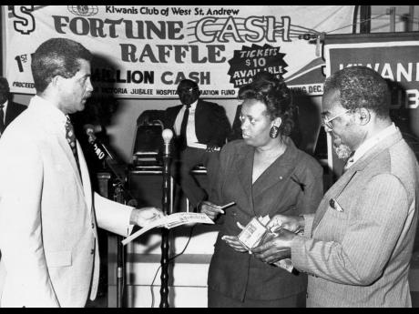 1991 PHOTO: Minister Easton Douglas (right) is seen digging deep into his wallet to purchase 10 tickets from Kiwanian Edgar Abbott (left) to symbolically declare open a Kiwanis Club of West St Andrew’s cash raffle to raise $500,000 for the Victoria Jubil