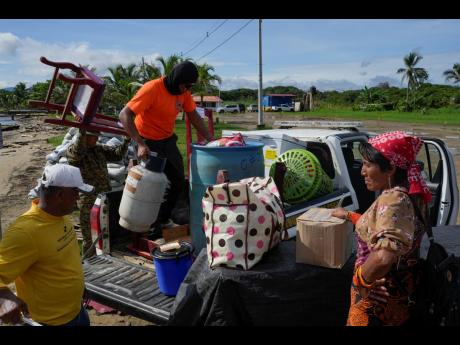 Civil protection officials (left), load a family’s belongings on a truck to move from the island of Gardi Sugdub, located off Panama’s Caribbean coast, to Nuevo Carti on the mainland on Wednesday.
