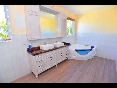 The principal bathroom with a marble countertop sink cabinet and a glass-window whirlpool tub (with its own television and radio).