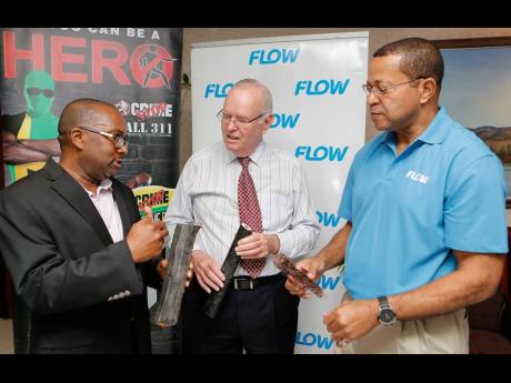 From left: In this February 2017 photo, Ronnie Thompson, FLOW’s senior director of customer experience, discusses copper theft plaguing the company with Major General Robert Neish, chairman of Crime Stop, and Christopher Bryan, FLOW’s manager of securi