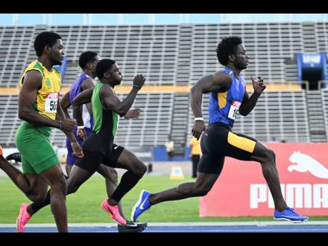 Elite Performance track club’s Javorne Dunkley (right) steps away from his chalengers during the running of the 100 metres at the Carifta Trials inside the National Stadium yesterday.