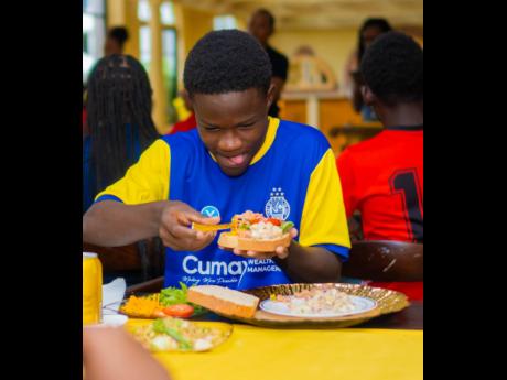 Harbour View Football player Zaire Douse is in the zone as he prepares his smoked chicken sandwich with tomatoes, lettuce, and red onions.