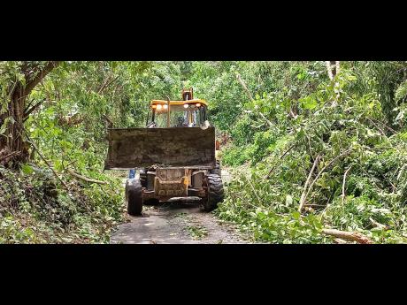 Credit: Photo by Gareth Davis Sr A tractor clearing a blocked roadway near Priestmans River in East Portland on Thursday.
