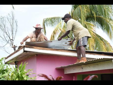 Edwin Powell (left) and Anthony Powell repairing the roof of a neighbour in Bull Savannah, St Elizabeth, after sheets of zinc blew off during the passage of Hurricane Beryl last Wednesday.