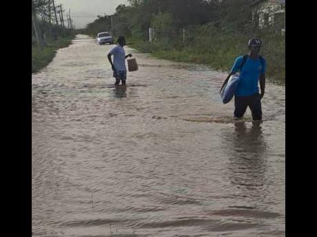 Residents wading the floodwaters on Mahoe Street in Hill Run, St Catherine, after flooding on Sunday.