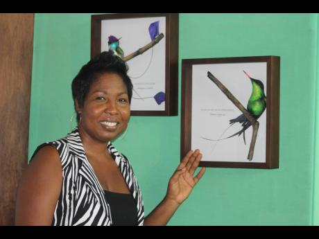 Symerna Blake of Antillean Charm displaying some of her framed ceramic pieces.
