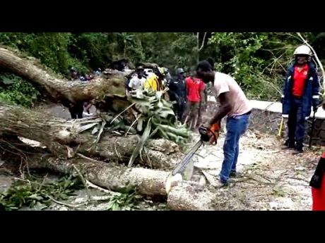 Credit: Gareth Davis Sr Firefighters clearing sections of the roadblock along the corridor in Junction, St Mary, on Monday.
