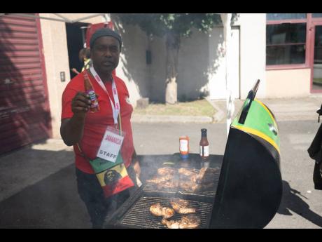 Restaurateur and caterer Wayne Smith shows off a bottle of Grace hot pepper sauce as he mans the jerk pan outside of Jamaica House in Paris, France.