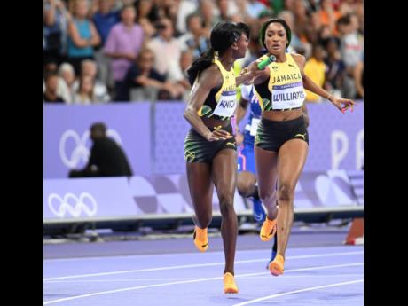 Stacey-Ann Williams (right) hands the baton to Andrenette Knight during the women’s 4x400-metre relay on the final day of athletics at the Paris Olympics inside the Stade de France yesterday.