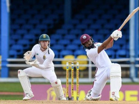 
Jomel Warrican (right) strikes a lusty blow to help prop up the West Indies first-innings total during a Test match against South Africa at the Queen’s Park Oval yesterday. South Africa’s Kyle Verreynne looks on.