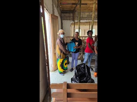 Credit: Contributed Leila Henry Riley (left), retired teacher and former resident of Rose Street in Lucky Hill, St Mary, visits the community on behalf of the overseas-based organisation Helping Others Pursue Excellence to distribute back-to- school supplies to children.