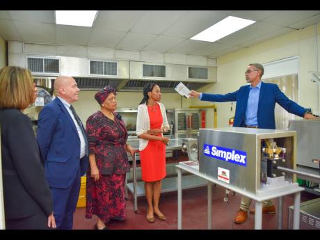 Director of the Jamaica Business Development Corporation (JBDC) Incubator and Resource Centre, David Harrison (right), leads a tour of the agro-processing incubator, located at the centre, at the grand opening in November 2023.  From left are Permanent Sec