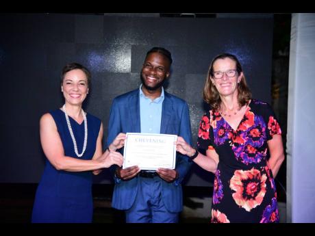 Credit: Antoine Lodge/Photographer Najae Murray (centre) collects his Chevening scholarship certificate from Senator Kamina Johnson Smith (left), minister of foreign affairs and foreign trade, and Judith Slater, British high commissioner to Jamaica, at the Windrush Gardens, British High Com