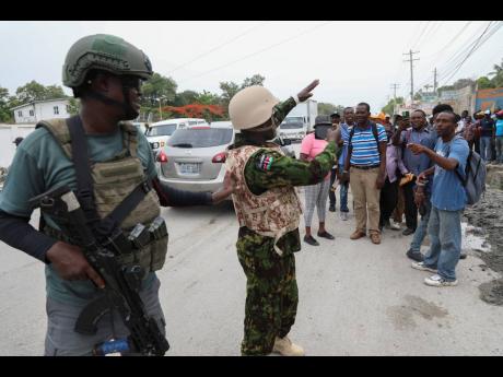 A Kenyan police officer takes candid photos of a group of Haitians welcoming the officers, in Port-au-Prince, July 3.