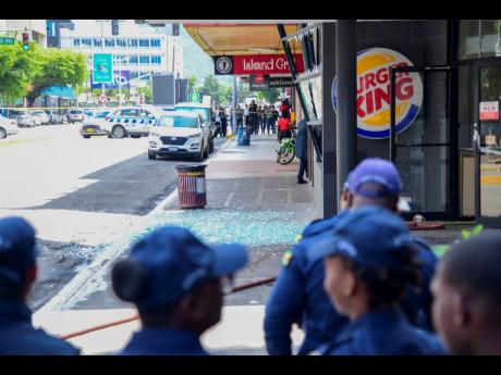 Members of the Jamaica Fire Brigade and the Jamaica Constabulary Force processing the scene on Knutsford Boulevard in New Kingston, where an explosion occurred at the Burger King outlet yesterday. 
