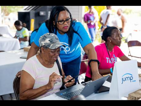 Credit: Contributed Carol Robertson, senior business development partner for C&W Business, assists a JUMP signee at the Girl Guides Association of Jamaica headquarters in Kingston, recently.