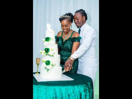 Credit: Miguel Gayle Photography Opting for a striking green dress for the reception, the bride joins her groom in the traditional cake-cutting ceremony, featuring a creation made with love by Okiem Dallas of Yaady Kitchen 876.