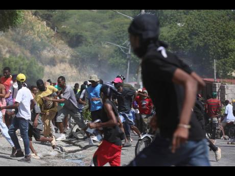People run from tear gas fired by police to disperse protesters demanding police and the prime minister take immediate action against gangs in Port-au-Prince, Haiti, Monday, August  19.