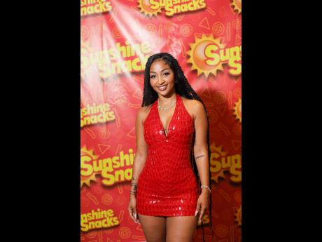 Shenseea takes a moment to smile at the camera, wearing a bold red dress that is on brand with one of Sunshine Snacks’ signature colour.