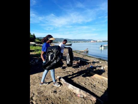 WPM Waste Management Limited team members Sharnon Williams (left) and Andrew Hart clear discarded waste from the Fisherman’s Beach in St James, during International Coastal Clean-up (ICC) Day on Saturday, September 21. 