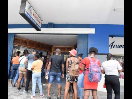 Persons wait in line to get inside the Kingston Bookshop on King Street in downtown Kingston to purchase school books. Keith Duncan writes: Achieving the fiscal balance targets and the debt reduction strategies will become challenging and will require sign