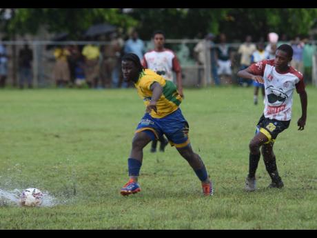 Rusea’s High School’s Damar Sailman (left) tries to shake the attentions of Anchovy High School’s Malik Timberlake during their ISSA/WATA daCosta Cup Zone B encounter at the Collin Miller Sports Complex in Lucea yesterday.