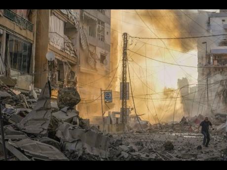 A man runs for cover as a smoke rises in the background following an Israeli airstrike in Dahiyeh, Beirut, Lebanon, yesterday.
