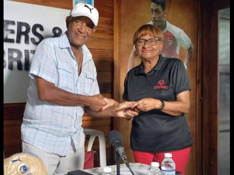 Clive ‘Busy’ Campbell (left) of Masters and Celebrities receives a donation from Lorna Bell, the widow of Jackie Bell, at the media launch of the annual Bell-Ziadie Memorial Football Festival at Football Factory on Thursday.  