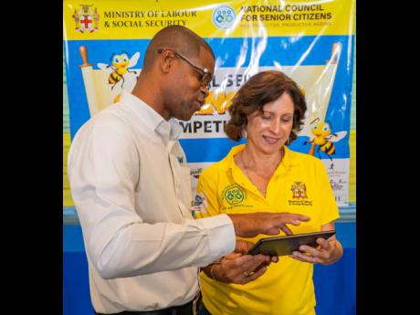 Courtney Bell, community programme coordinator of the Flow Foundation, shows newly minted winner of the National Senior Spelling Bee competition, Juliet Salmon, the features of her new Samsung tablet. The Flow Foundation presented prizes to the top three c