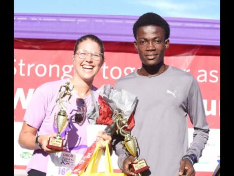 Tonya Busse (left) and Evan Tetteh (right), female and male winners of the  in the  CIBC Caribbean’s Walk for the Cure Run/Walk are photographed with their trophies .