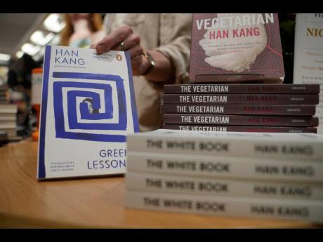 A book store employee handles books by the South Korean writer Han Kang in London. Kang has been awarded the Nobel Prize for Literature.
