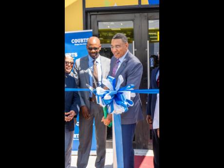 Prime Minister Andrew Holness cutting the ribbon for the opening of the new multimillion-dollar Courts Drax Hall store in St Ann on Thursday.