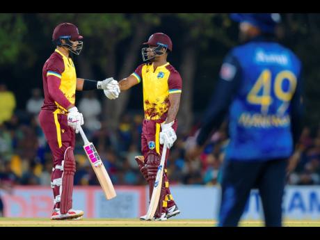West Indies’ Brandon King and Evin Lewis bump fists during the first Twenty20 cricket match against Sri Lanka in Dambulla, Sri Lanka, yesterday.
