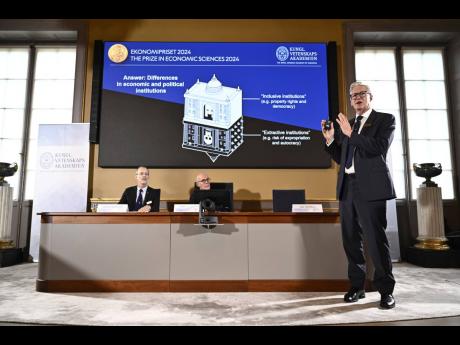 Academy of Sciences permanent secretary Hans Ellegren, centre, Jakob Svensson, left, and Jan Teorell, of the Nobel assembly announce the Nobel memorial prize in economics winners, Daron Acemoglu, Simon Johnson and James A Robinson, during a press meeting a