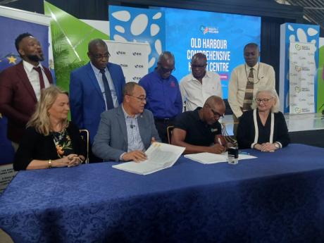 Health & Wellness Minister Dr Christopher Tufton (seated, second left) and various stakeholders in the construction of a new US$6-million comprehensive health centre in Old Harbour, St Catherine, take part in yesterday’s signing ceremony. In back row (fr