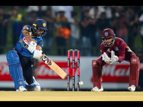 Sri Lanka’s Kamindu Mendis (left) plays a shot during the first ODI cricket match between against the West Indies in Pallekele, Sri Lanka on Sunday. Looking on West Indies wicketkeeper Shai Hope.