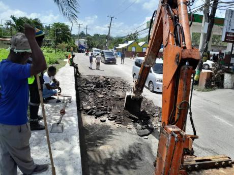 Credit: Bryan Miller A team of workmen monitoring the use of heavy-duty equipment to fix the Lucea main road, in Hanover.
