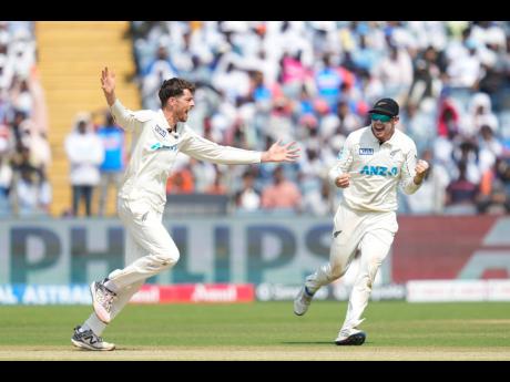 
New Zealand’s Mitchell Santner (left) and his captain Tom Latham celebrate the dismissal of India’s Virat Kohli during the day three of the second Test between the teams at the Maharashtra Cricket Association Stadium, Pune, India, yesterday. 