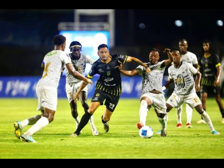Credit: Concacaf photo Gustavo Ascona (centre, 22) of Moca attempts to dribble past several Cavalier players during the Concacaf Caribbean Cup semi-final first leg at the Moca 85 Stadium, in Moca, Dominican Republic on Thursday night.