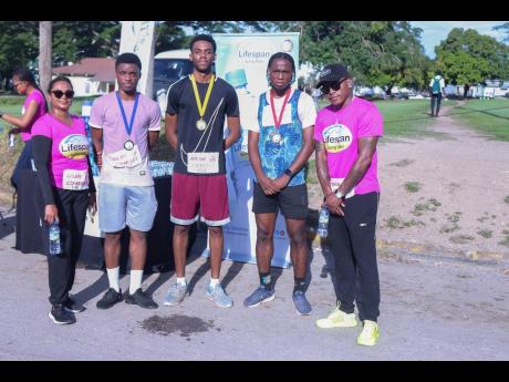 Male winners in the UWI Guild Pink Run Matthew Hutchinson (1st), Rolando Rednan (2nd), Jaheim Murdock (3rd), pose for photos with Nayana Williams (left), CEO Lifespan, and Olaf Blackwood (right), Lifespan Ambassador.