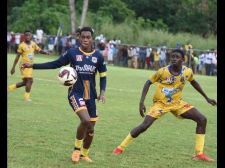 Munro College’s Antwone Smith (left) controls the ball ahead of Clarendon College’s Romario Thompson during their ISSA/WATA daCosta Cup round-of-16 clash at Munro College playing field on October 30.